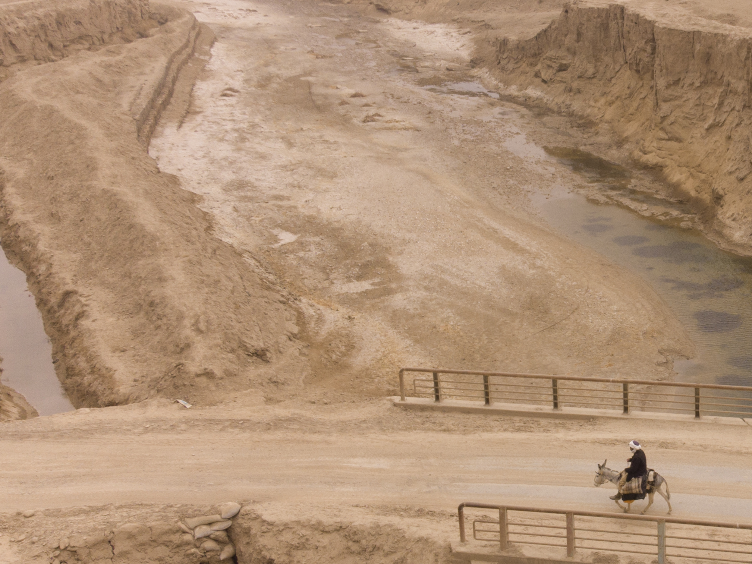caption: An Afghan farmer uses a donkey to carry water canisters across the dried-out river near Sang-e-Atash, Afghanistan. A severe drought has dramatically worsened the already desperate situation in the country.