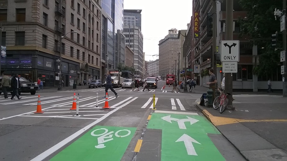 caption: At the north end of this cycle track, signage suggests that cyclists turning left on Pike dismount and cross two streets before rejoining traffic.