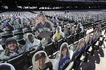 caption: A Seattle Mariners worker places a fan cutout in a seat at the team's ballpark as part of the "Mariners Seat Fleet" in place of real fans, Monday, July 27, 2020, in Seattle. The Mariners open play at home against the Oakland Athletics on Friday.