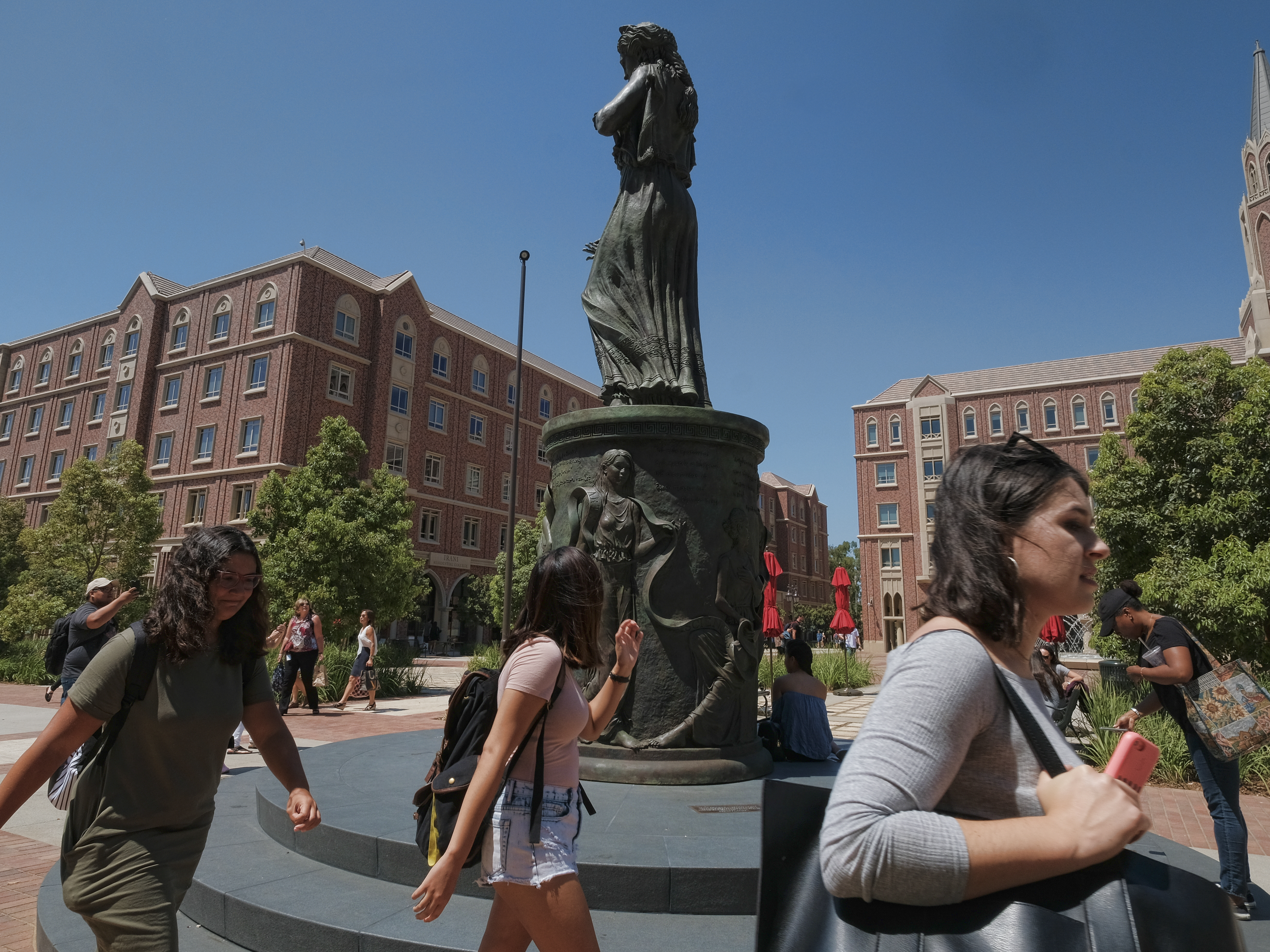 caption: Students walk by the statue of Hecuba, the legendary Queen of Troy, with a quote by William Shakespeare — spelled "Shakespear" — on the campus of the University of Southern California in Los Angeles in 2017.