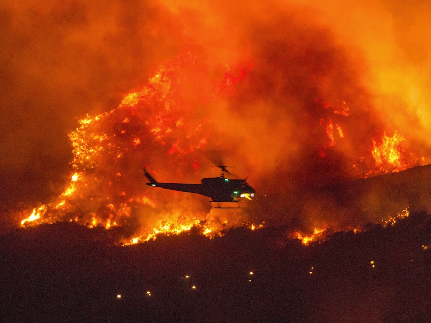 caption: A helicopter prepares to drop water at a wildfire in Yucaipa, Calif., on Sept. 5. A firefighter was killed in the El Dorado blaze on Thursday.