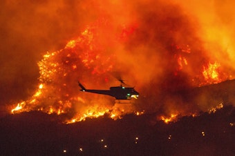 caption: A helicopter prepares to drop water at a wildfire in Yucaipa, Calif., on Sept. 5. A firefighter was killed in the El Dorado blaze on Thursday.
