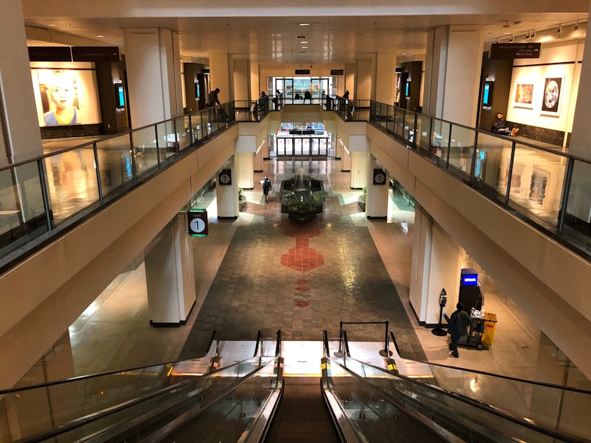 caption: At the Washington State Convention Center, a few people sitting on benches are the only visitors