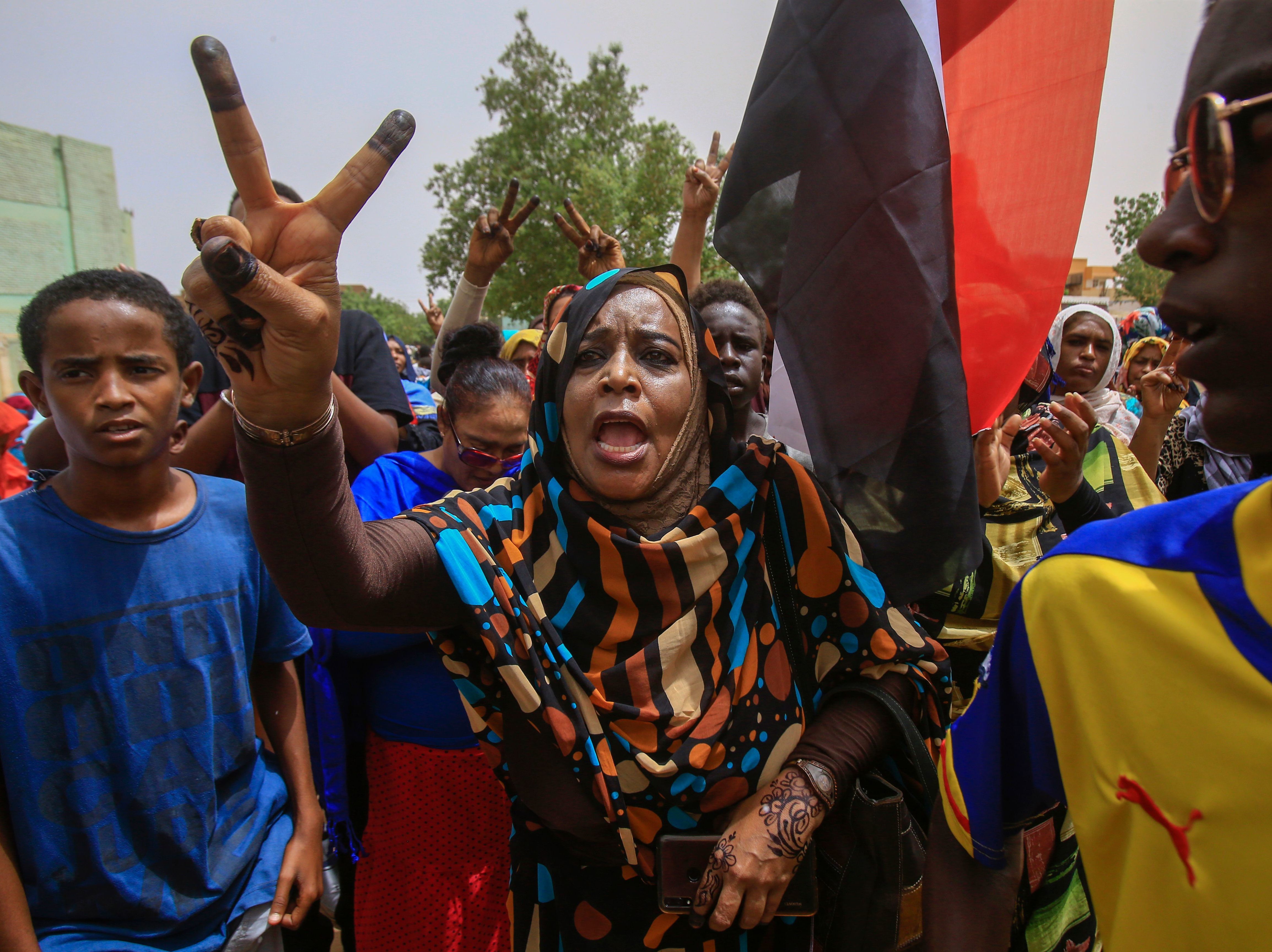 caption: Sudanese protesters flash the V-sign during a mass demonstration in Khartoum on Sunday against Sudan's ruling generals.