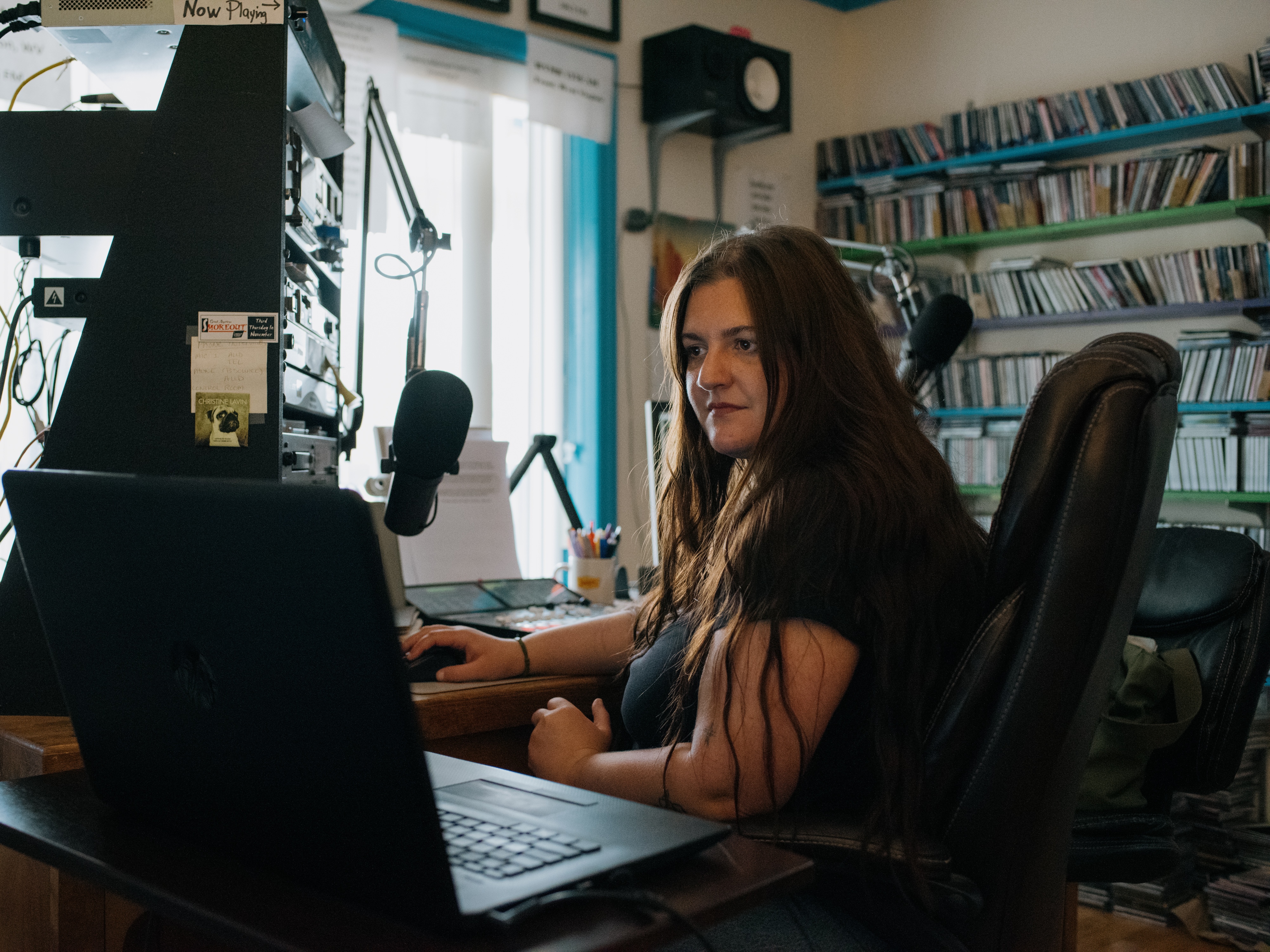 caption: Abby DuFour, WCHG news reporter and afternoon host of the show <em>DuFour Du Jour</em>, cues up the next song in her broadcast at the station in Hot Springs, Va.