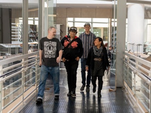 caption: Leah Esguerra (right), who is credited with being the first social worker installed directly at a public library, strolls through the fifth floor of the San Francisco Public Library's main branch, joined by the library's health and safety associates (from left to right) Sidney Grindstaff, Jennifer Keys and Cary Latham.