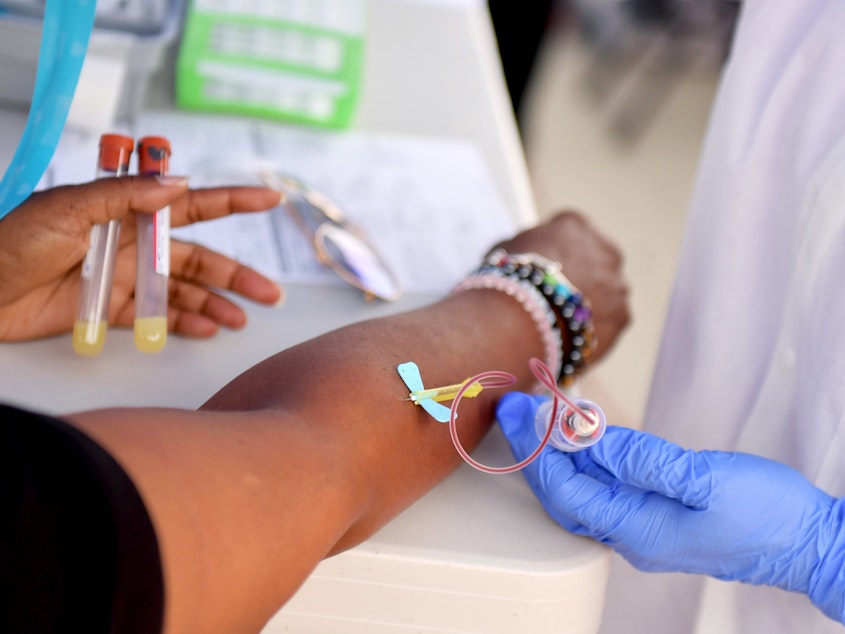 caption: A medical worker draws blood at a free COVID-19 SARS-CoV-2 serology antibody testing community event in Los Angeles on Wednesday.