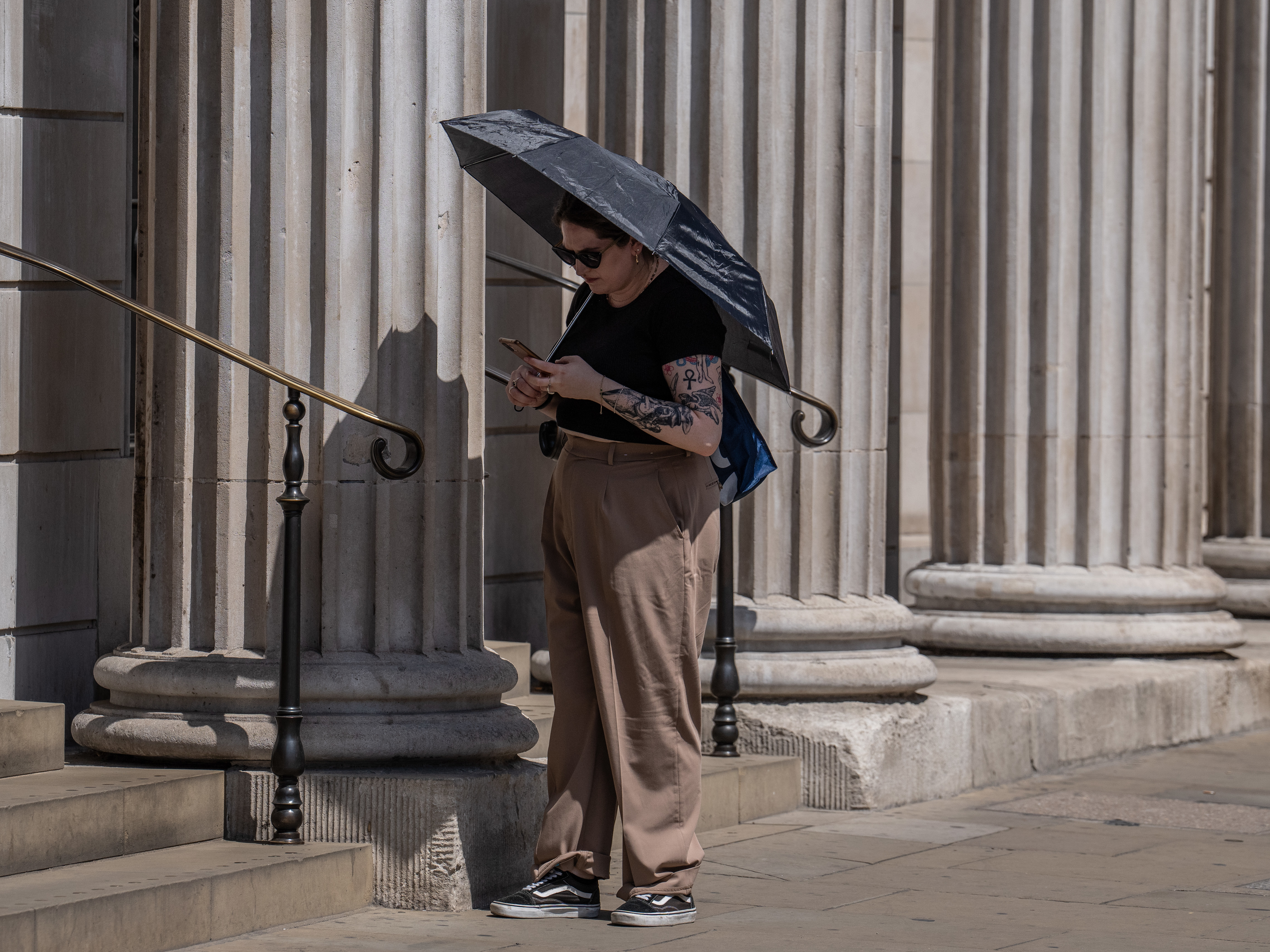 caption: A woman shelters from the sun under a dark umbrella in London on Monday. Temperatures are forecast to hit well over 100 degrees in parts of the U.K. on Monday and Tuesday.