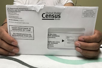 caption: A Rhode Island resident holds an envelope he received for the 2020 census test run in Providence County.
