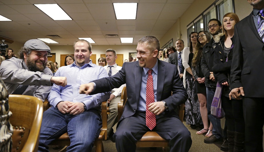 caption: Sean Green, seated right, is congratulated by Sean Fitzgerald, left, as Scott O'Neil looks on before Green is issued his new Washington state legal marijuana license Wednesday, March 5, 2014, in Olympia, Wash.