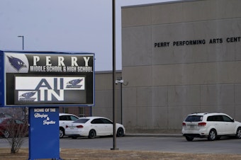 caption: Vehicles are seen in a parking lot outside of Perry High School in Iowa the day after a shooting on Jan. 4, 2024. Dan Marburger, the school's principal who put himself in harm's way to protect students during the shooting, died Sunday, Jan. 14, 2024, a funeral home confirmed after Marburger's after the family announced it on a GoFundMe page.