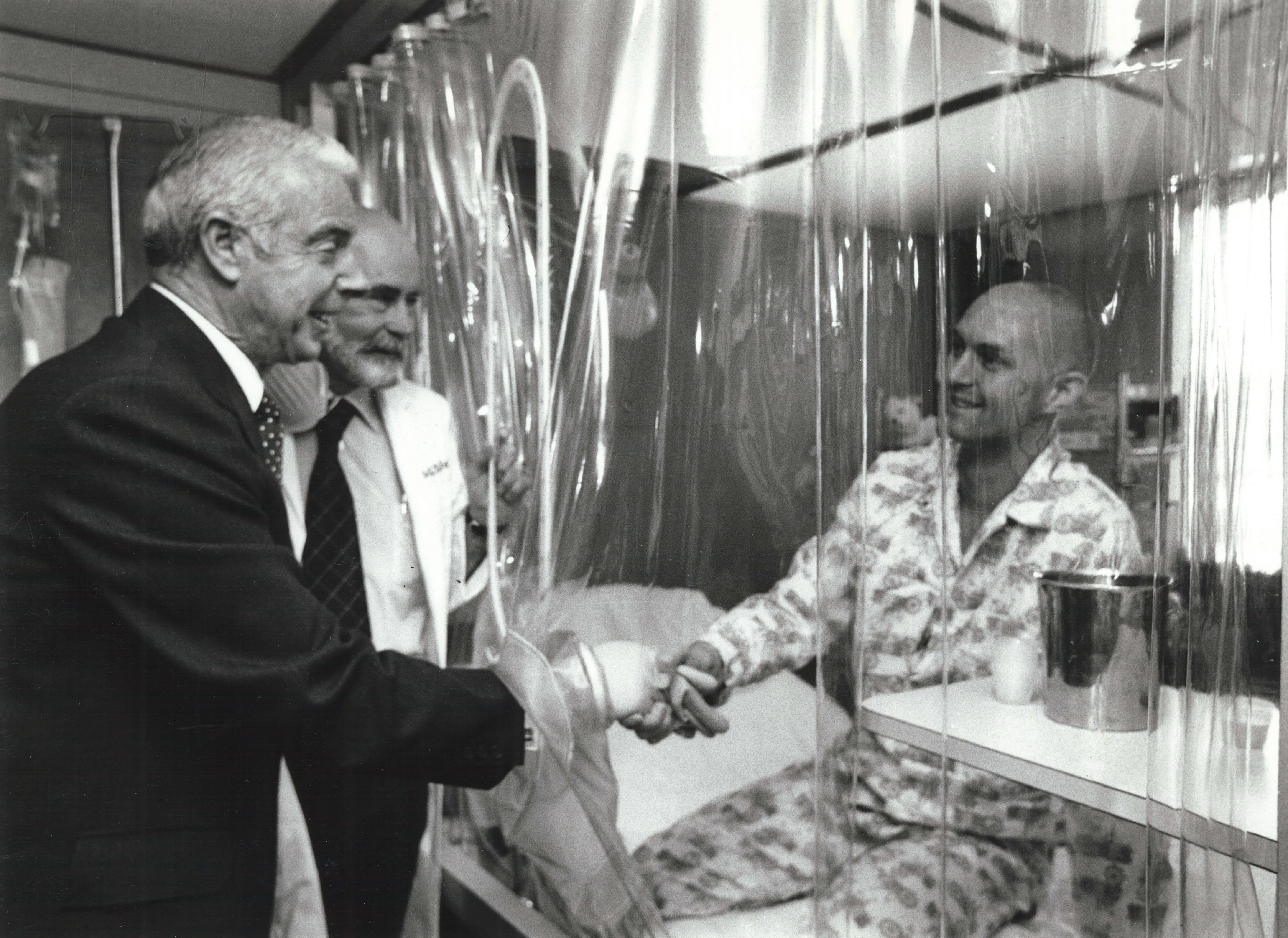 caption: Baseball legend Joe DiMaggio, left, and Dr. E. Donnall Thomas are  greeted by bone marrow transplant patient Darrell Johnson in a LAF  (laminar airflow) room, at the Fred Hutchinson Cancer Research Center, in Seattle, 1978.