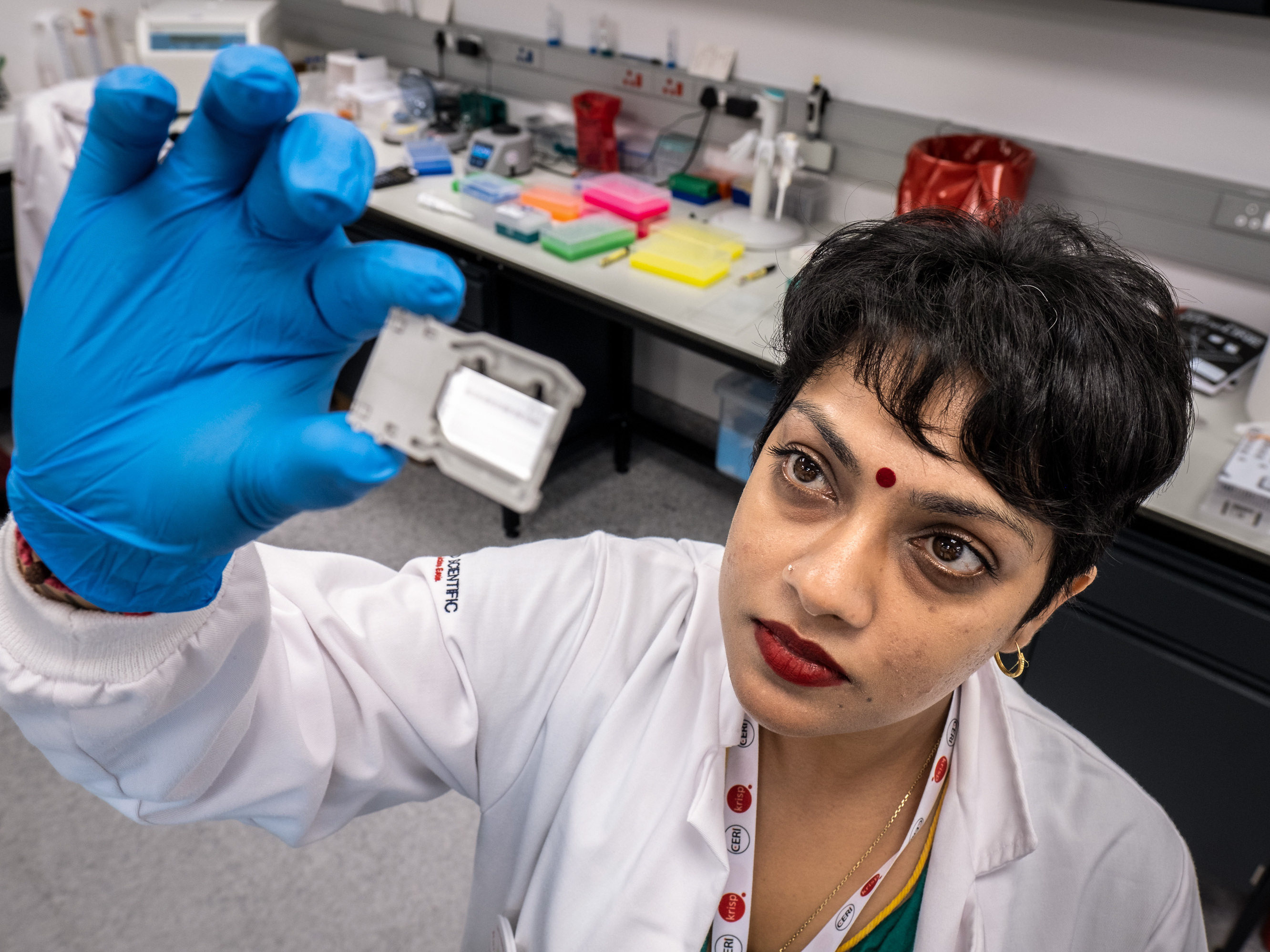 caption: Yeshnee Naidoo prepares a "flow cell" for analysis by one of the center's many genetic sequencing machines.