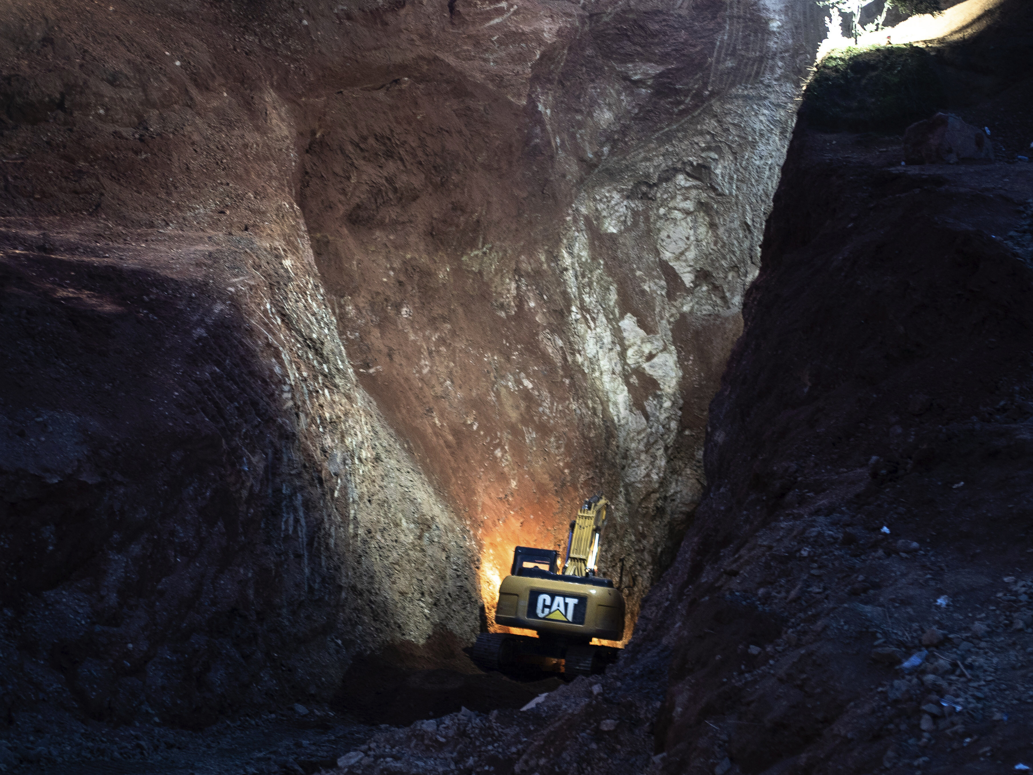 caption: Heavy equipment is used to dig through a mountain on Friday during an attempt to rescue a boy trapped in a well.