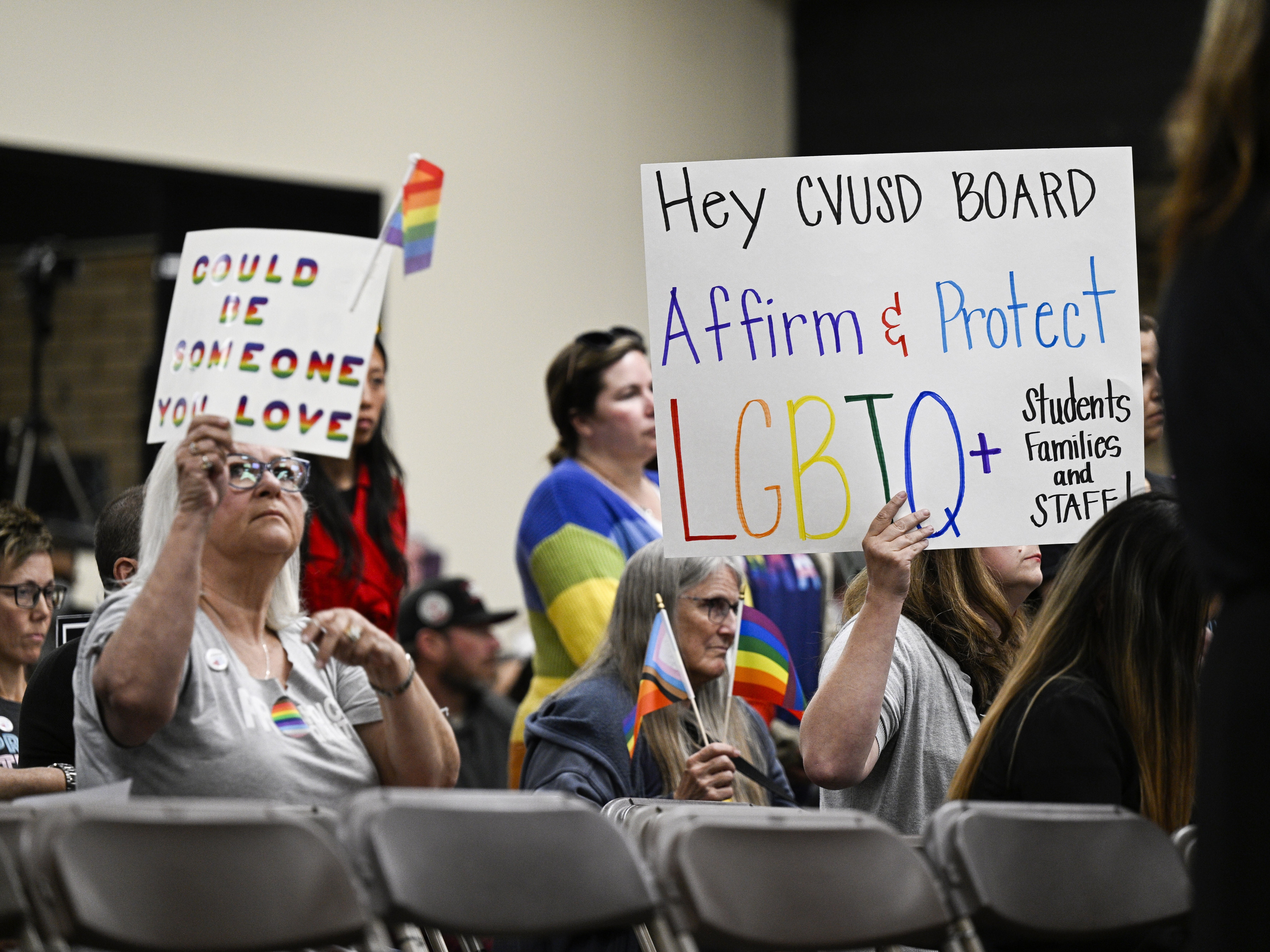 caption: Parents, students, and staff of Chino Valley Unified School District hold up signs in favor of protecting LGBTQ+ policies at Don Antonio Lugo High School, in Chino, Calif., in June 2023. California Gov. Gavin Newsom signed a law Monday barring school districts from passing policies that require schools to notify parents if their child asks to change their gender identification.