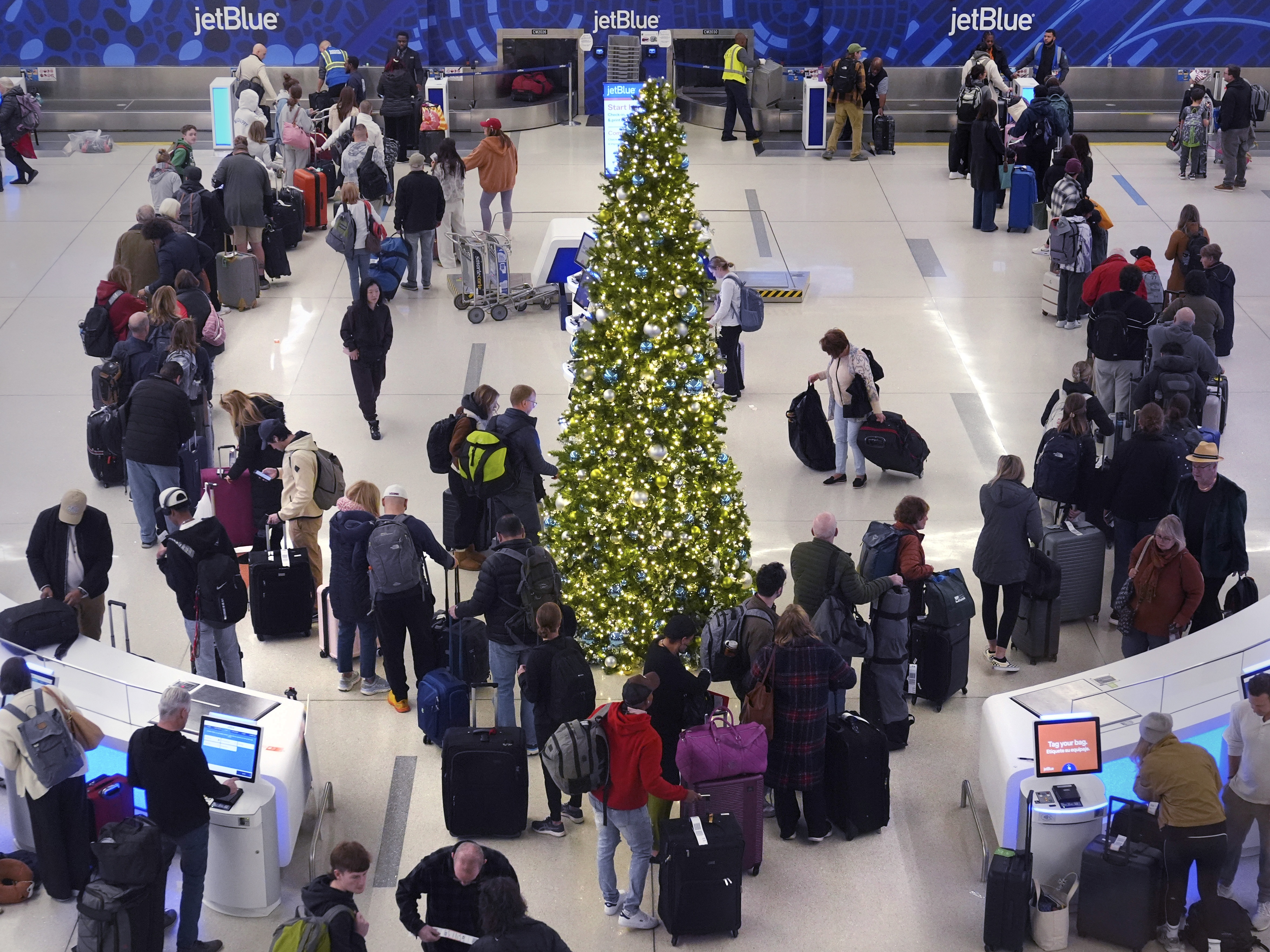 caption: Holiday travelers wait in line to check their bags at the JetBlue terminal at Boston's Logan Airport on Friday.