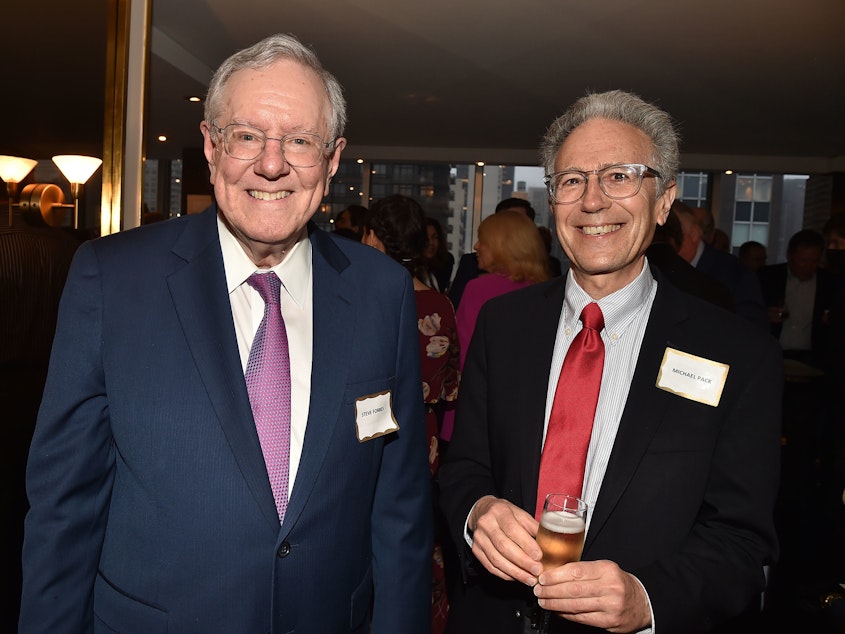 caption: A federal investigation found former U.S. Agency for Global Media CEO Michael Pack (at right) repeatedly engaged in abuses of power and gross mismanagement. Pack, shown last year at a party with conservative politician and publisher Steve Forbes, sought to stamp out all hints of anti-Trump sentiment at the agency, the Voice of America, and other networks funded by the federal government.