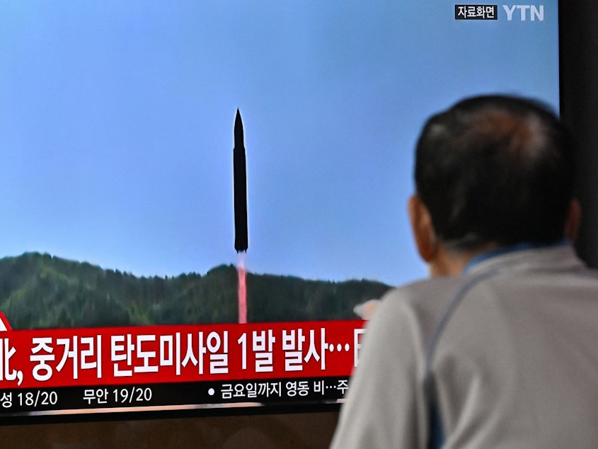 caption: A man watches a television screen showing a news broadcast with file footage of a North Korean missile test, at a railway station in Seoul on October 4, 2022.