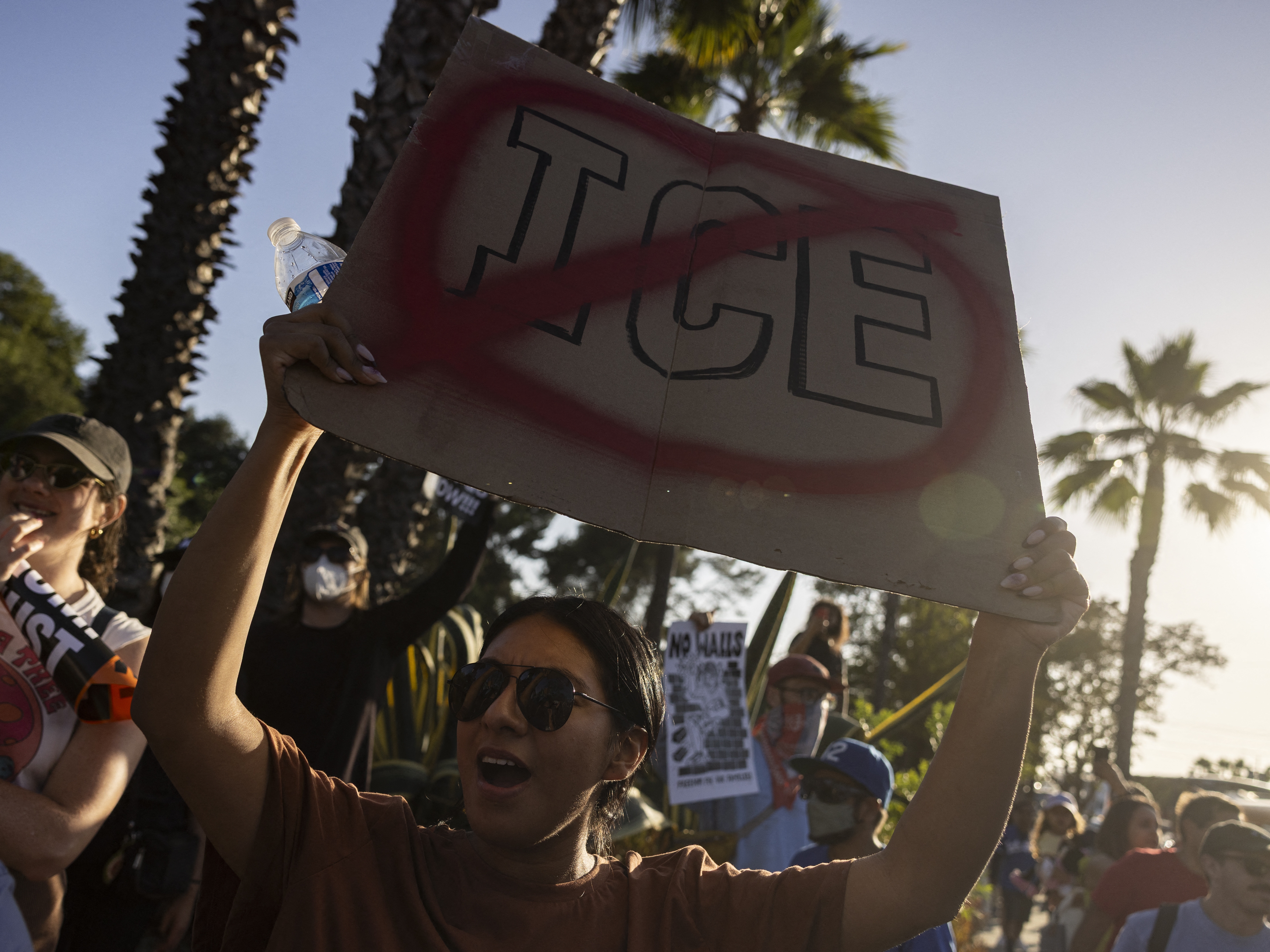 caption: A demonstrator holds up a sign as they protest in front of the main entrance of Dodger Stadium on Thursday.