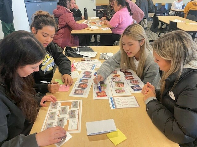 caption: High school students taking part in the University of Washington's annual MisInfo Day in March 2024 They are looking at pictures of faces to tell whether the images were created with generative AI tools or authentic.