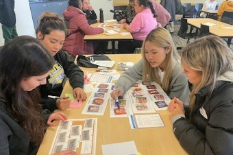 caption: High school students taking part in the University of Washington's annual MisInfo Day in March 2024 They are looking at pictures of faces to tell whether the images were created with generative AI tools or authentic.