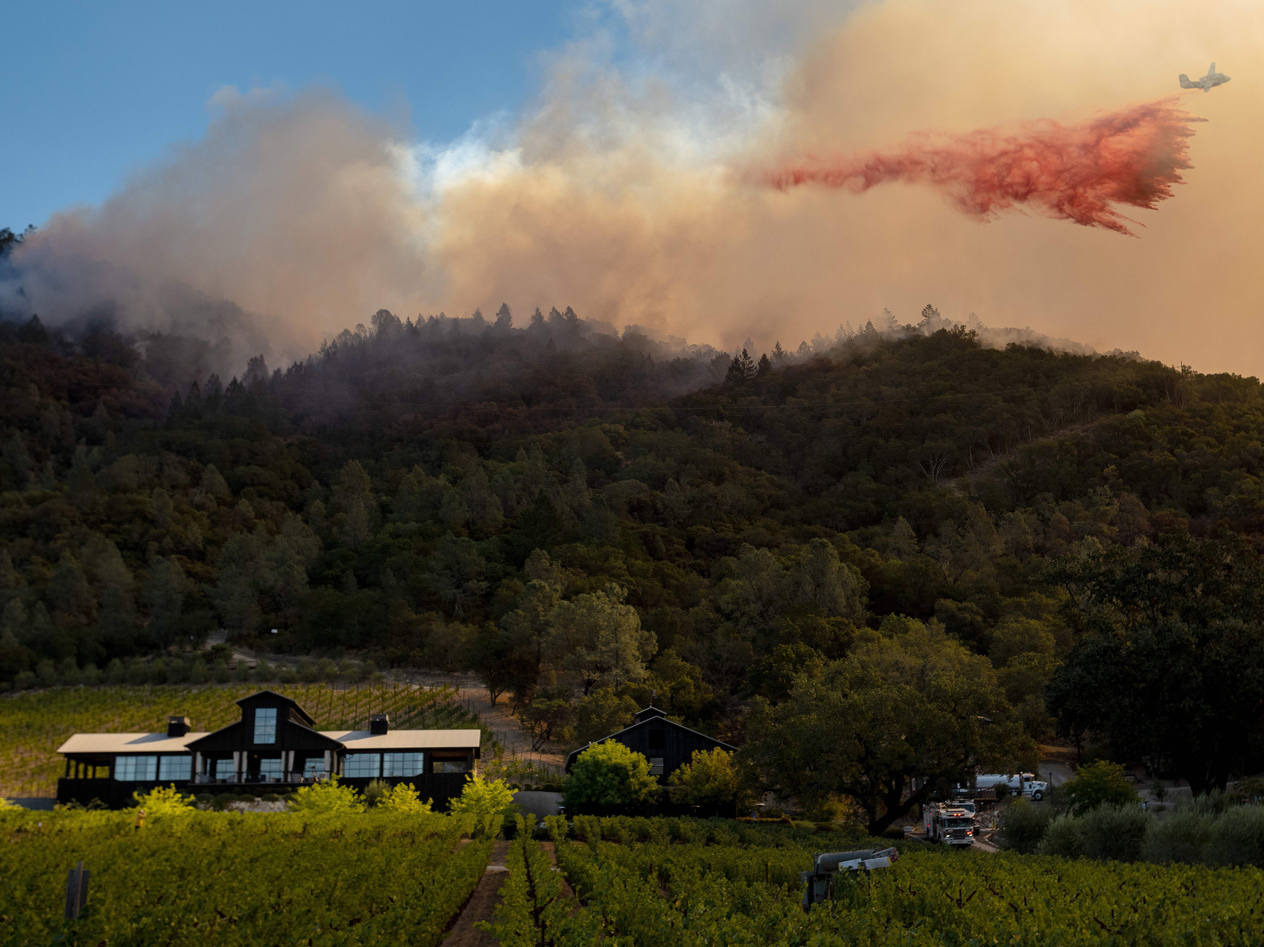 caption: A California Department of Forestry and Fire Protection airplane drops fire retardant along a burning hill during the Glass Fire in Calistoga, Calif., in September. California is one of two states to require wildfire risk be disclosed to new homebuyers.