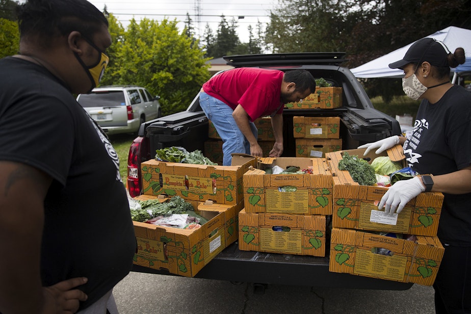 caption: Boxes of fresh produce, meat and dairy are loaded into the back of a truck before being delivered to families at a drive-thru free food distribution site led by the Pacific Islander Community Association of Washington on Thursday, July 10, 2020, along Military Road South in Kent. 