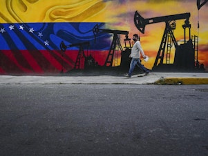 caption: A man walks past a mural featuring oil pumps and wells in Caracas, Venezuela, as the country faces the prospect of the U.S. reimposing oil sanctions.