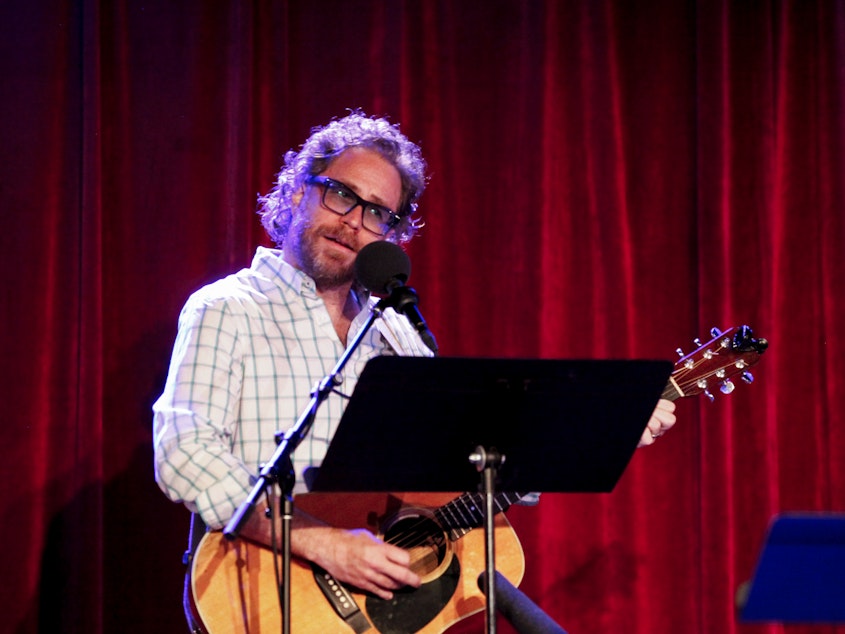 caption: <em>Ask Me Another</em>'s house musician Jonathan Coulton leads a music parody game alongside Ophira Eisenberg at the Bell House in Brooklyn, New York.