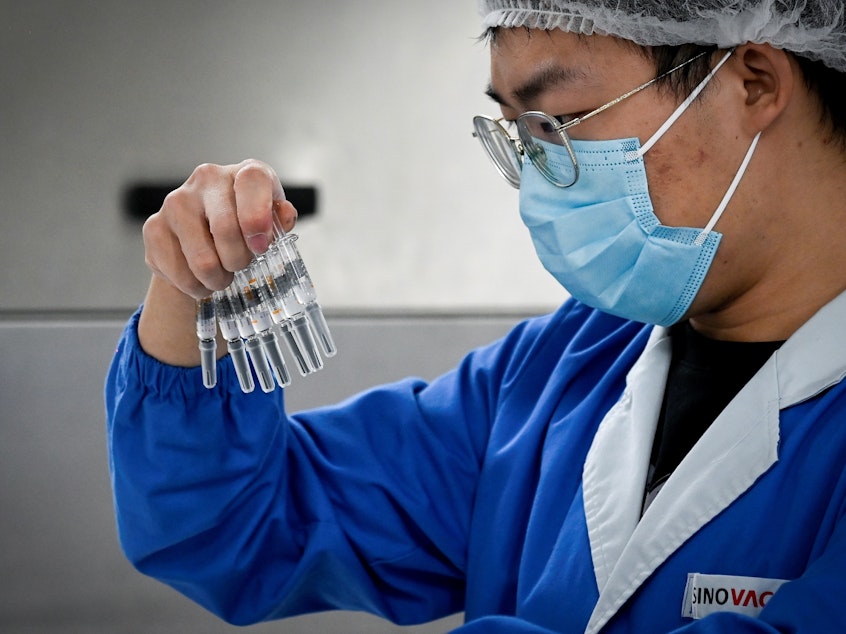 caption: A staff member checks vaccines at a Beijing factory built by Sinovac to produce a COVID-19 coronavirus vaccine. Sinovac is one of 11 Chinese companies approved to carry out clinical trials of potential vaccines.