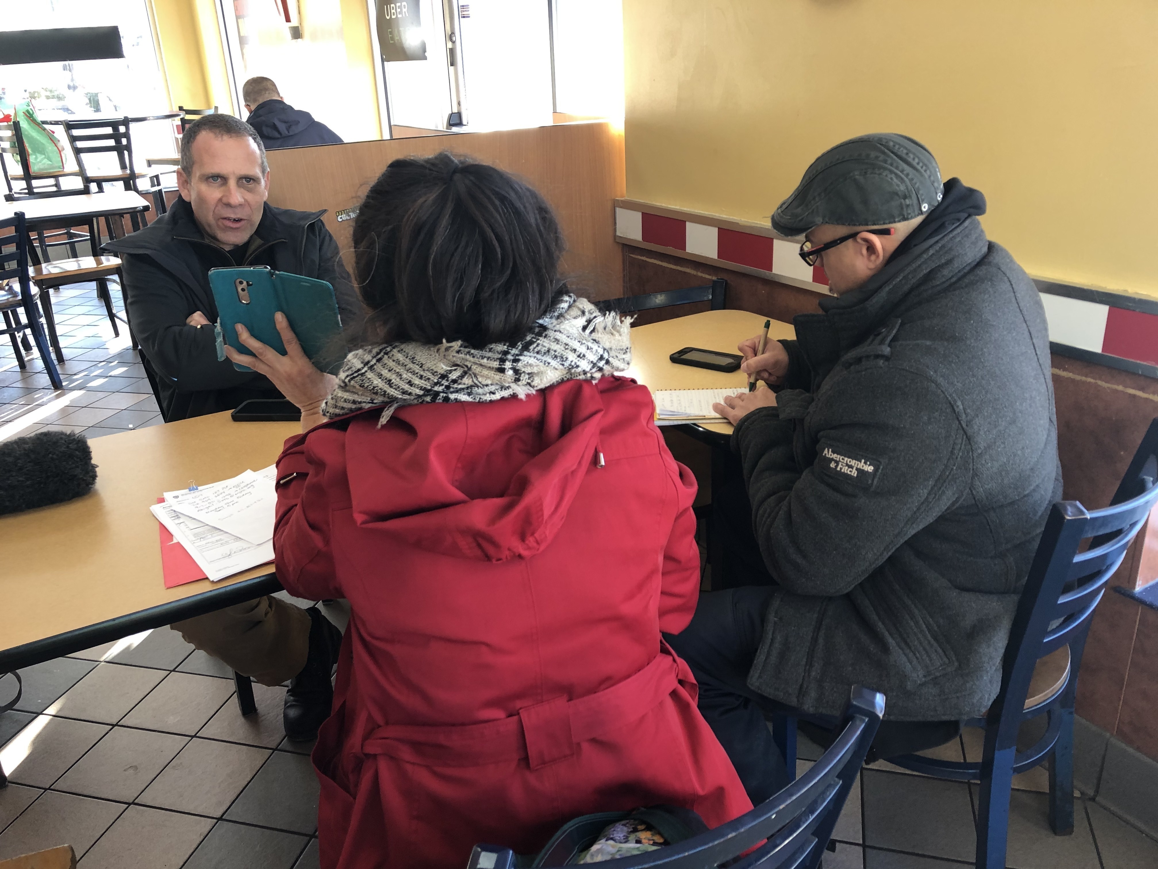 caption: Nick Selby and NYPD officer Luis Sayan interview a retired New York City teacher who lost more than $300,000 to online scammers posing as Chinese police.