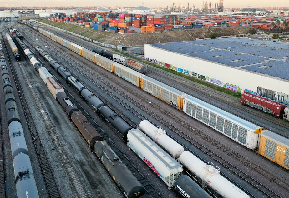 caption: In an aerial view, freight rail cars sit in a rail yard near shipping containers on Nov. 22in Wilmington, Calif.