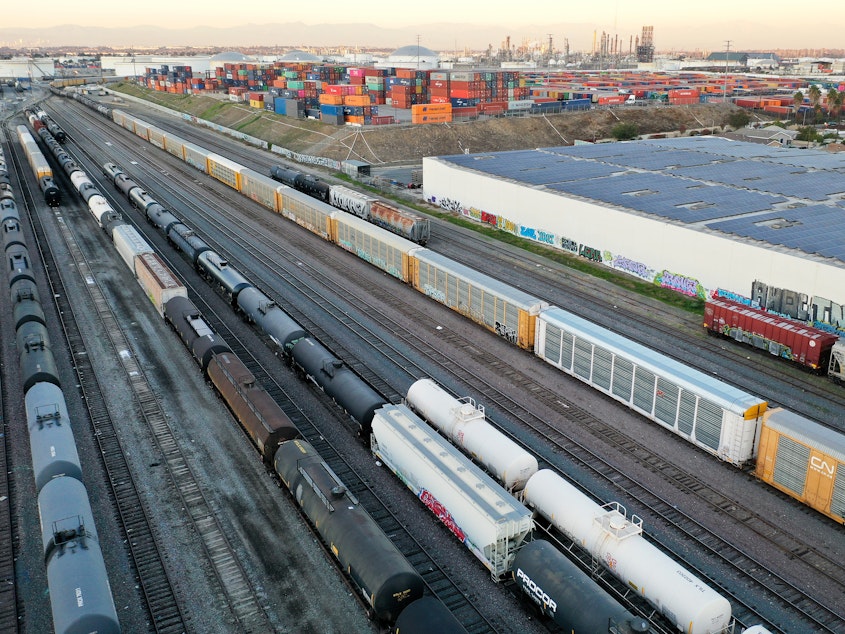 caption: In an aerial view, freight rail cars sit in a rail yard near shipping containers on Nov. 22in Wilmington, Calif.