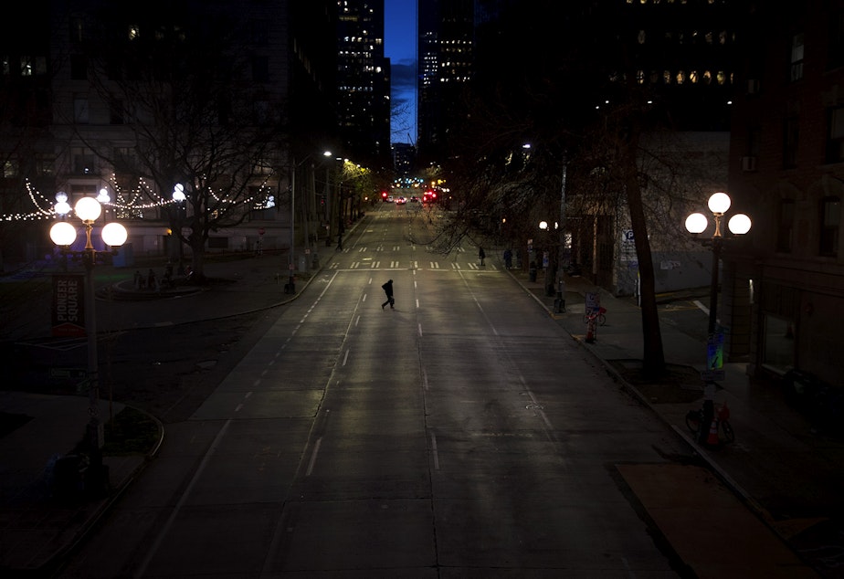 caption: A pedestrian crosses an empty 4th Avenue on Wednesday, March 25, 2020, in Seattle.