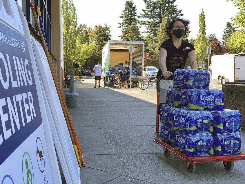 caption: A volunteer helps set up snacks at a cooling center established  to help vulnerable residents ride out the second dangerous heat wave to grip the Pacific Northwest last summer, on Aug. 11, 2021.
