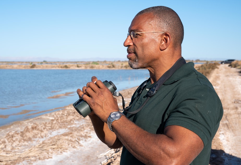 caption: Christian Cooper watches distant shorebirds at the Sonny Bono Salton Sea National Wildlife Refuge in California. The National Geographic channel has announced that Cooper will host a series called <em>Extraordinary Birder</em>. Cooper was in the spotlight after a woman in New York City's Central Park called the police and falsely accused him of threatening her in May 2020.