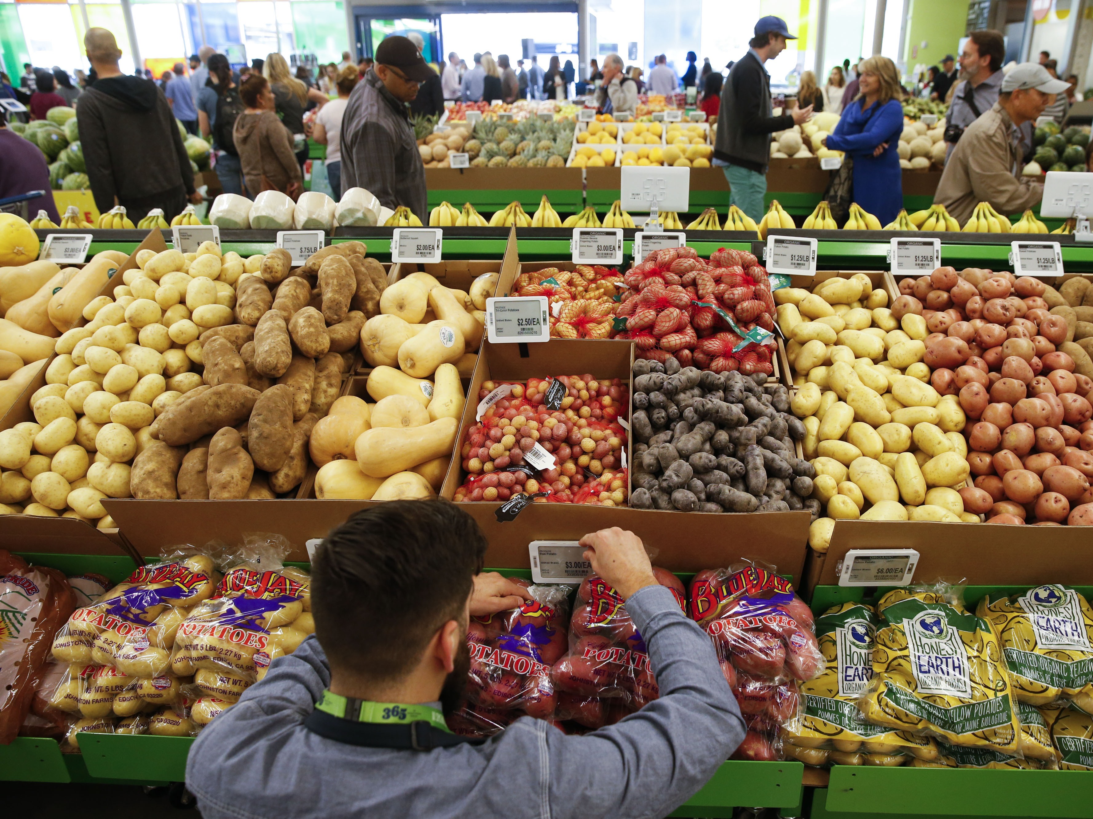 caption: An employee arranges a digital price tag for vegetables at the Whole Foods store in the Silver Lake neighborhood of Los Angeles.