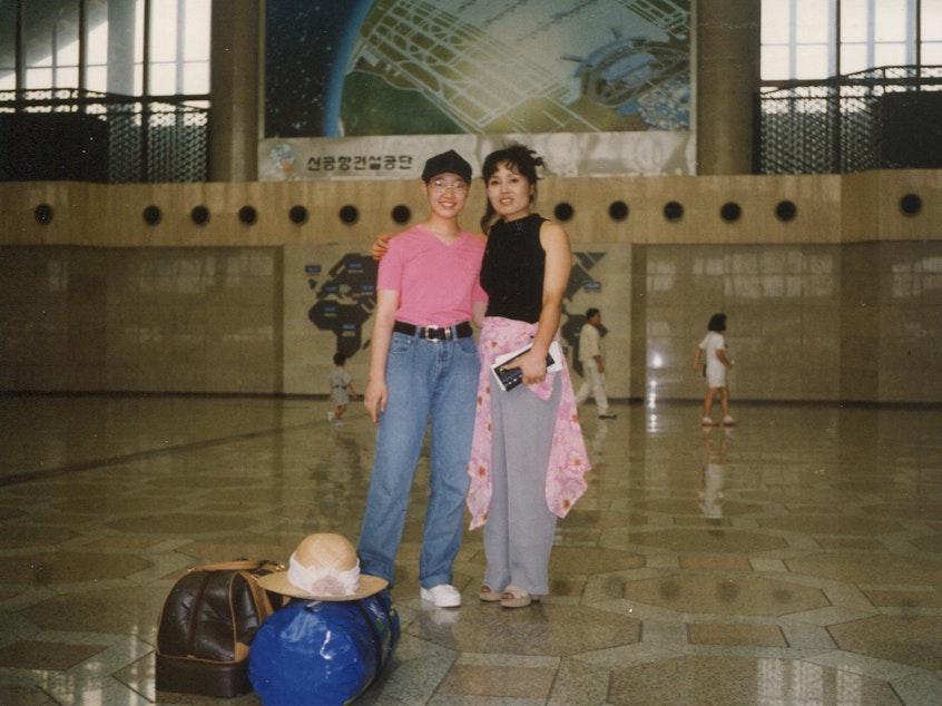 caption: Robin Ha and her mother, Cassie, at an airport in South Korea, on their way to the U.S., in 1995.