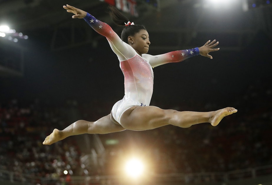 caption: Simone Biles, a 4'8" package of muscle, performs at an Olympic exhibition gala after having won four gold medals and one bronze in the 2016 Games. What she is wearing is not relevant.