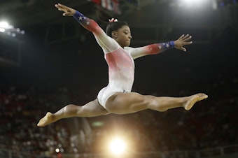 caption: Simone Biles, a 4'8" package of muscle, performs at an Olympic exhibition gala after having won four gold medals and one bronze in the 2016 Games. What she is wearing is not relevant.