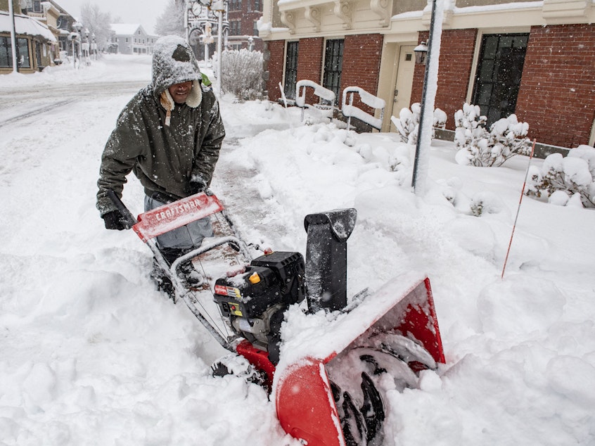 caption: A person uses a snowblower to clear snow in front of a home in Methuen, Mass., on Sunday.