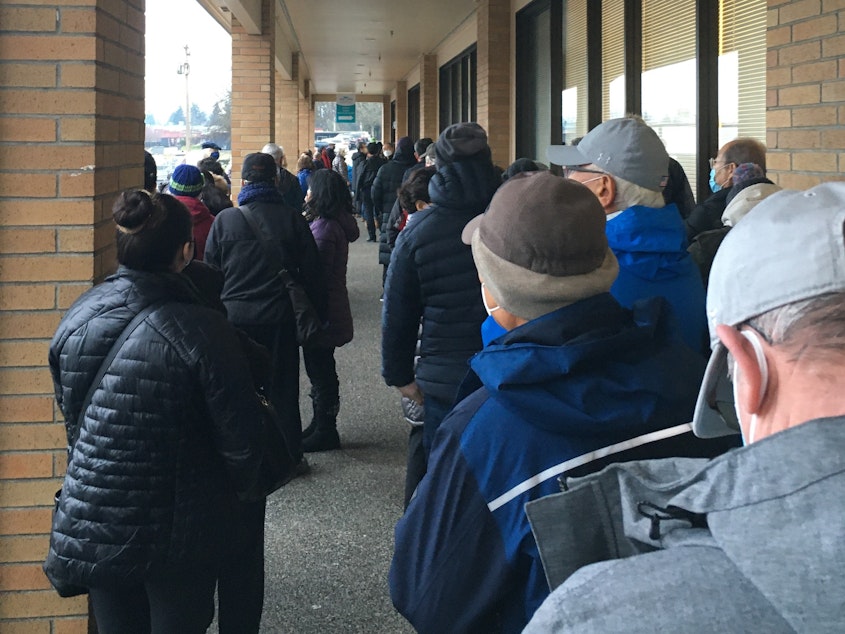 caption: People line up outside the Sea Mar clinic in Federal Way, January 21, 2021. The clinic is offering vaccine doses on a walk-in basis, subject to availability.