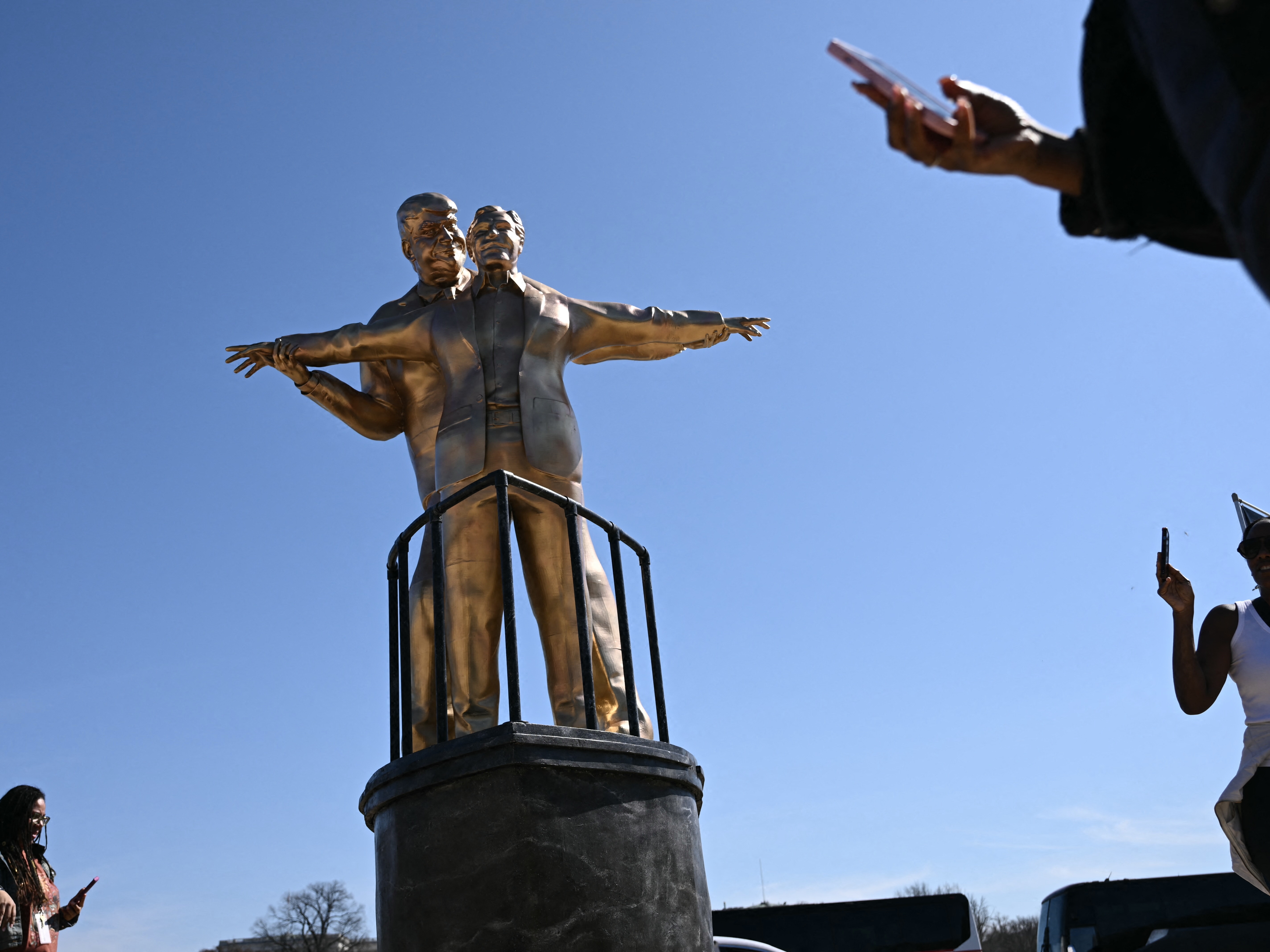 caption: A satirical statue of President Trump and the late convicted sex offender Jeffrey Epstein went up in front of the U.S. Capitol in February. The temporary statue drew huge crowds that amplified the image by posting it on social media. The statue is a play on the iconic scene from the film <em>Titanic</em> and is called "King of the World."