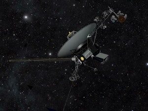 caption: This artist's impression shows one of the Voyager spacecraft moving through the darkness of space.