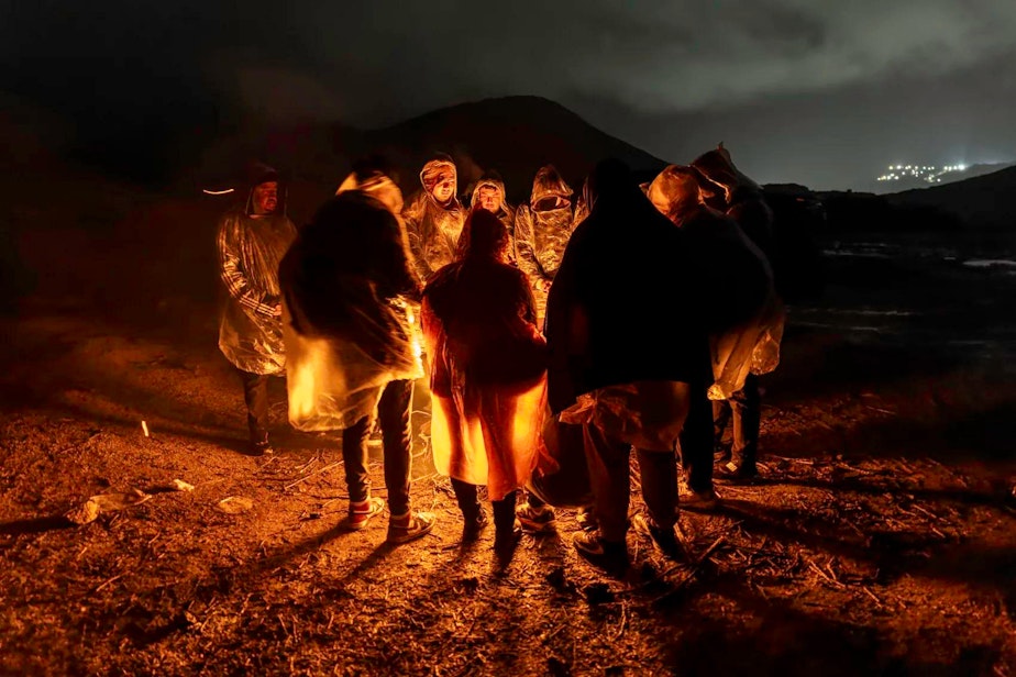 caption: Immigrants from Ecuador warm themselves after crossing the U.S.-Mexico border on March 6, in Campo, Calif. Migrants from Ecuador, China, Georgia and other nations waited for U.S. Border Patrol agents to collect them to process asylum claims.
