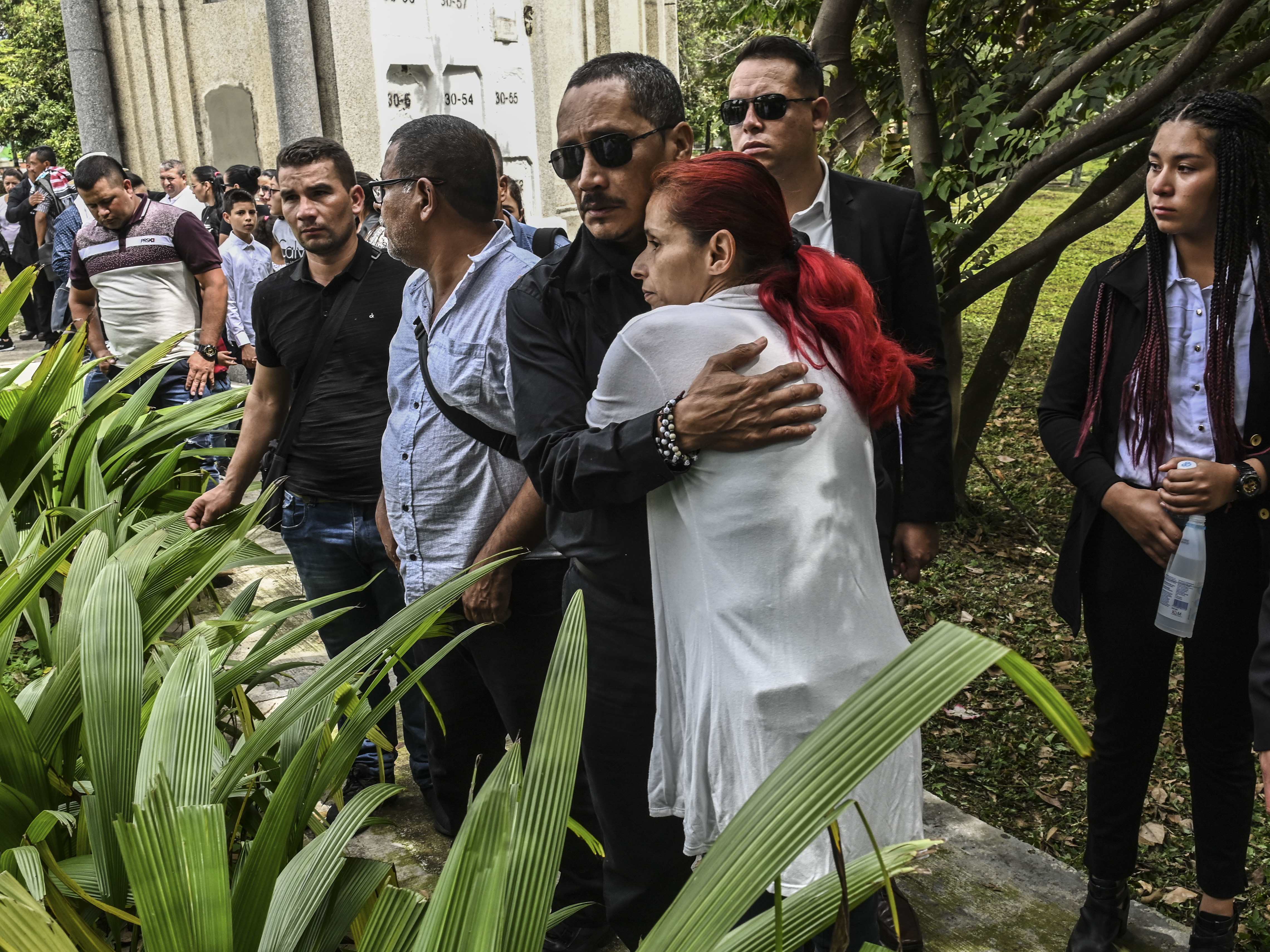 caption: Manuel Gonzales, a FARC political leader and former FARC commander, hugs a friend at the funeral of his son, former FARC guerrilla Manuel Antonio Gonzalez, in Medellin, Colombia, in December. Gonzales was shot dead near the Territorial Area of Training and Reincorporation for ex-FARC guerrillas.