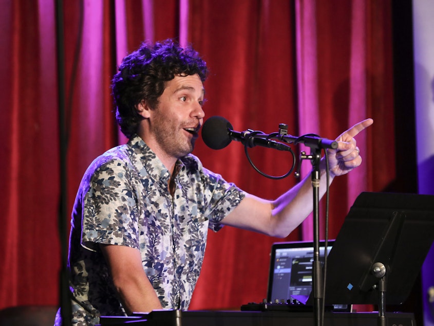 caption: Guest musician Julian Velard leads a music parody game on <em>Ask Me Another</em> at the Bell House in Brooklyn, New York.