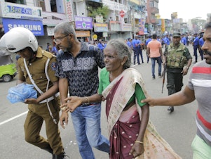caption: Sri Lankan elderly woman is helped near St. Anthony's Shrine after an explosion in Colombo, Sri Lanka, on April 21, 2019.