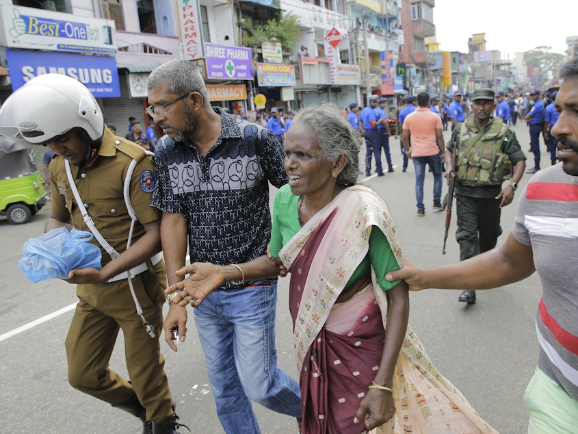 caption: Sri Lankan elderly woman is helped near St. Anthony's Shrine after an explosion in Colombo, Sri Lanka, on April 21, 2019.