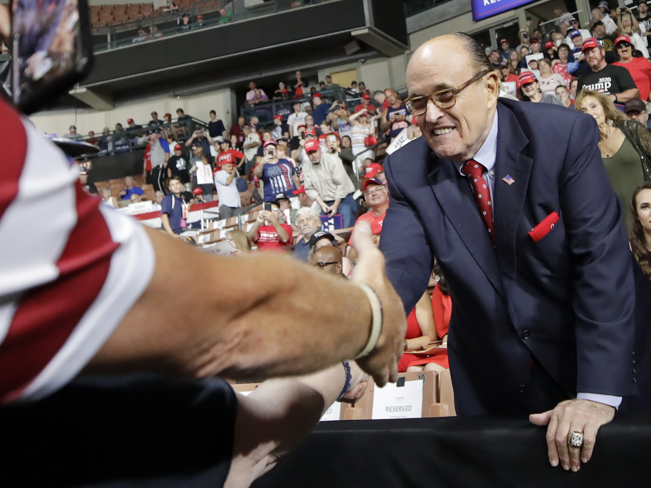 caption: Former New York City Mayor Rudy Giuliani shook hands with supporters as he arrived at President Trump's campaign rally on Aug. 15, 2019, in Manchester, N.H.